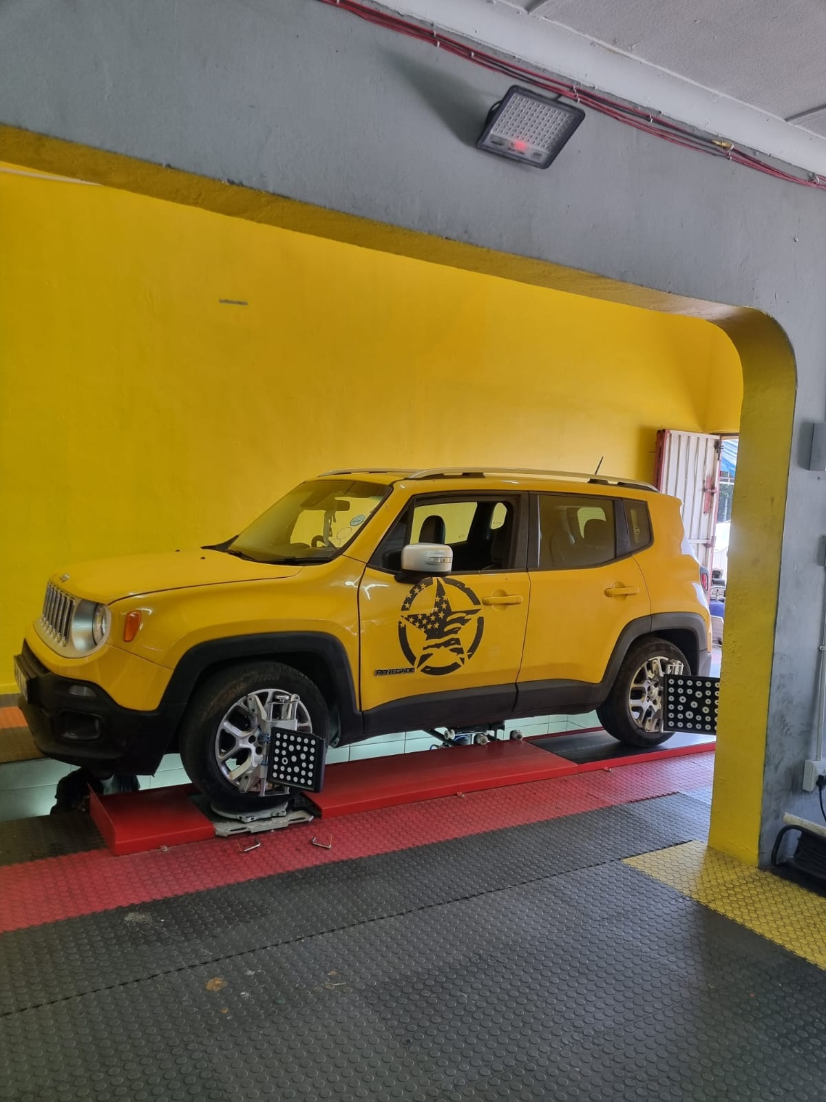 A yellow Jeep Renegade on the 3D wheel alignment ramp at Bong's Tyre Centre